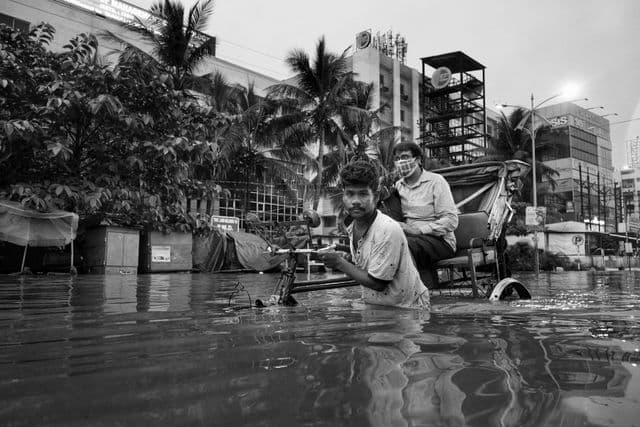 சூரத் நகரில் ஒரு ரிக்‌ஷா தொழிலாளி தனது வாடிக்கையாளரை கரை சேர்க்க முயல்கிறார்